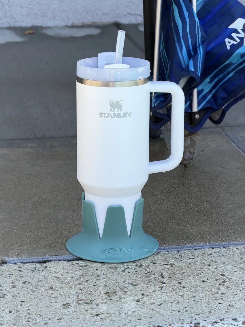 Real Stanley Quencher with straw seated in a Sage Steadi on a patio